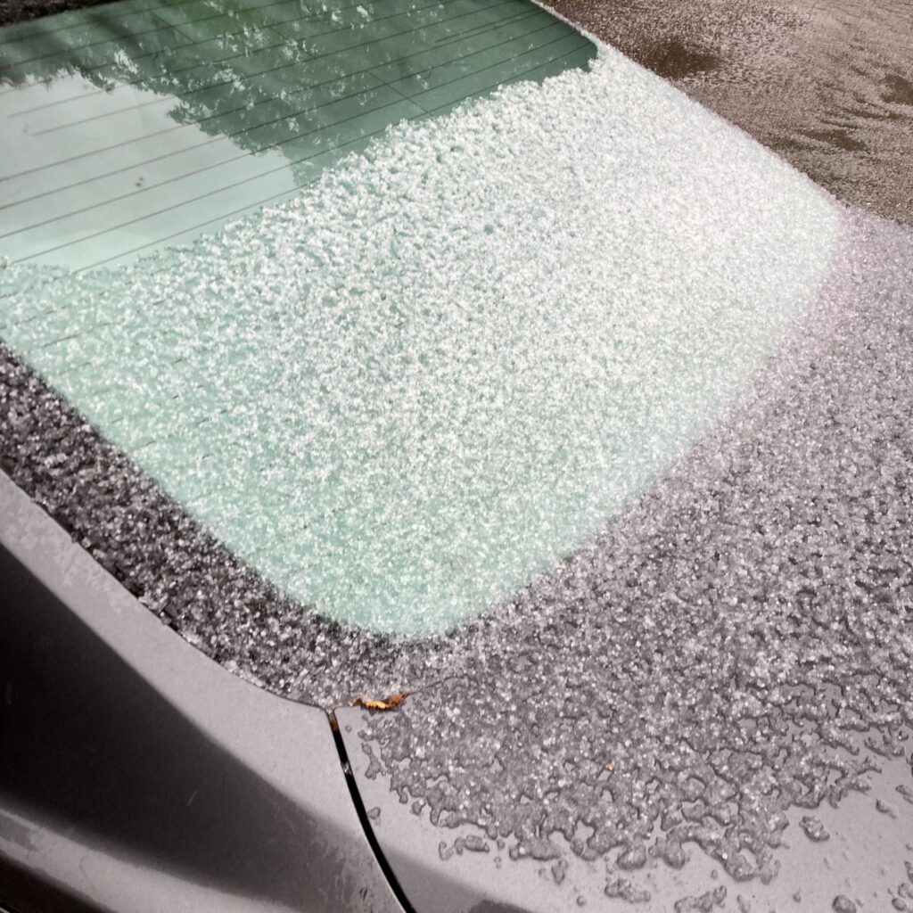 About an eighth of an inch of hail accumlated on the rear windshield of a car