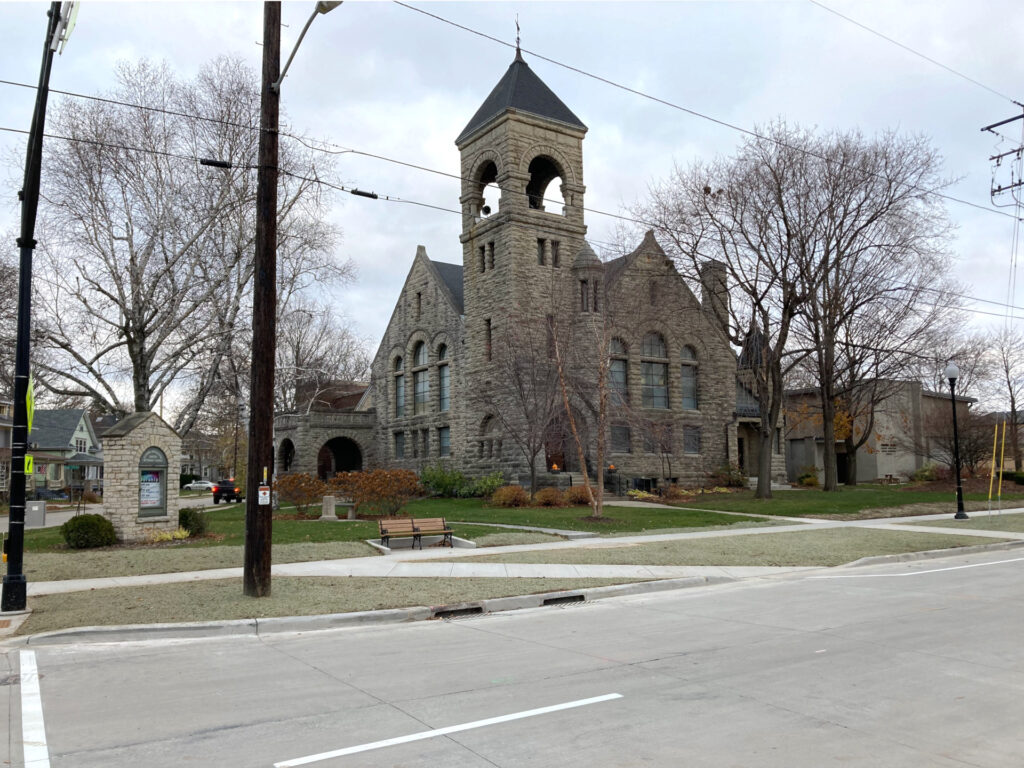 Older suburban or urban streetscape, large stone building with an imposing steeple