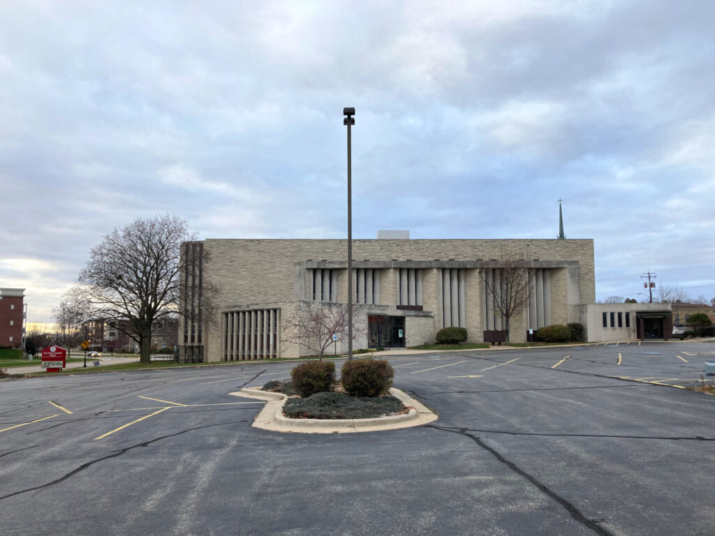 A modernist building viewed across an empty parking lot.