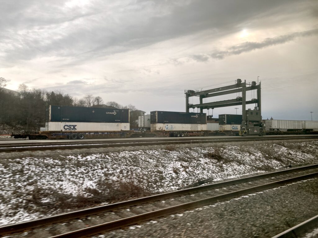 View from train window showing freight cars on another track.