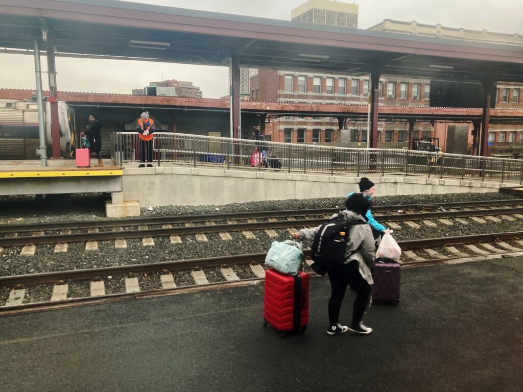 View from the train window showing people walking along damp pavement towards a ramp.