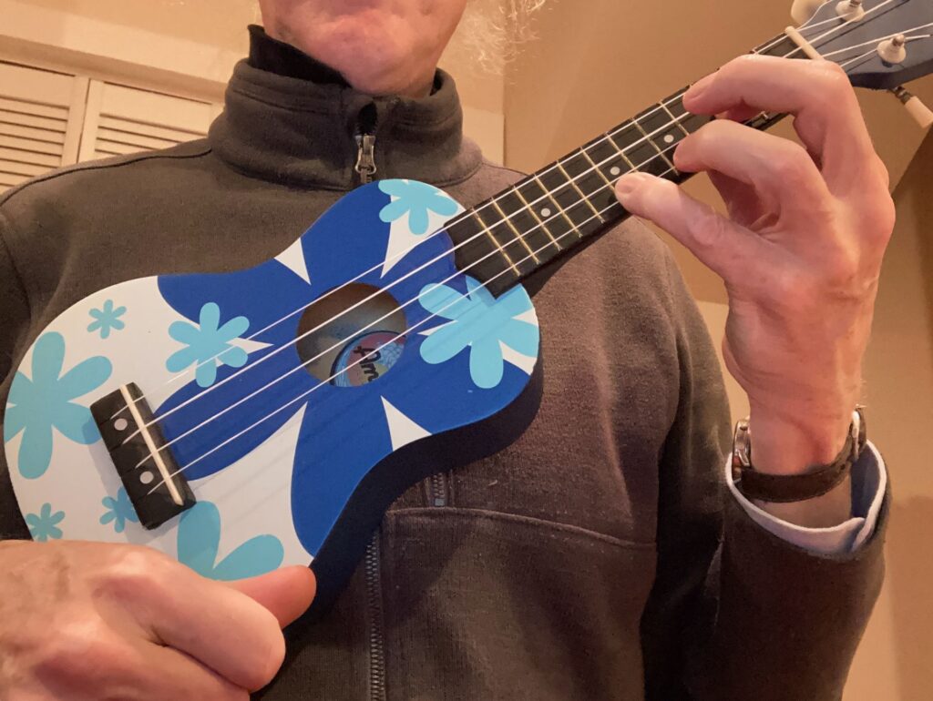 Me holding a ukulele with blue flowers painted on it.