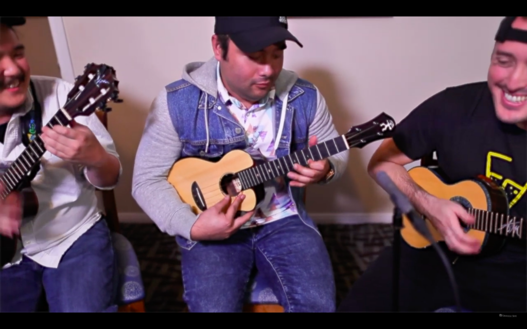 Screen grab from the video showing Kalei Gamaio soloing, flanked by Neal Chin and Andrew Molina, both of whom are smiling.