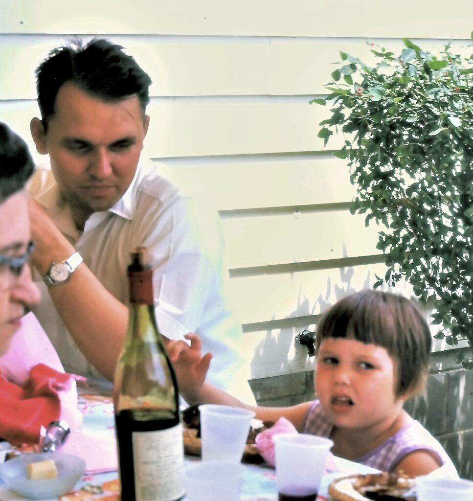 Man sitting at a picnic table looking at a young girl next to him.