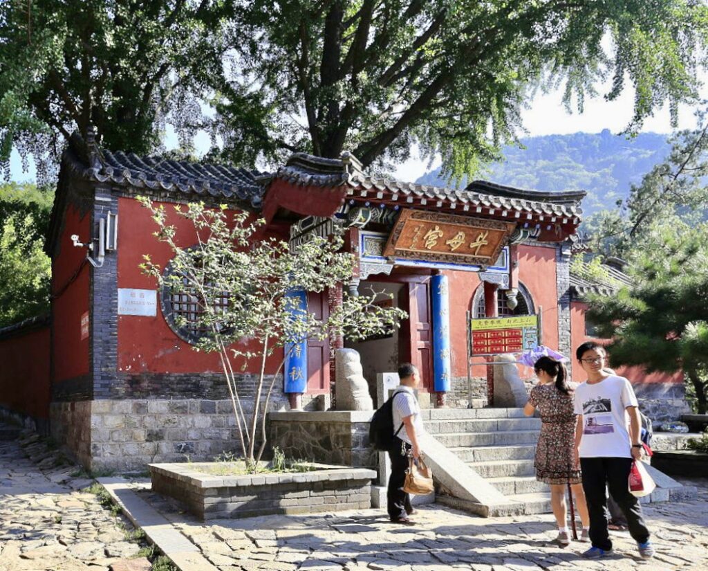 A modest building in the mountains, with tourists in front of it.