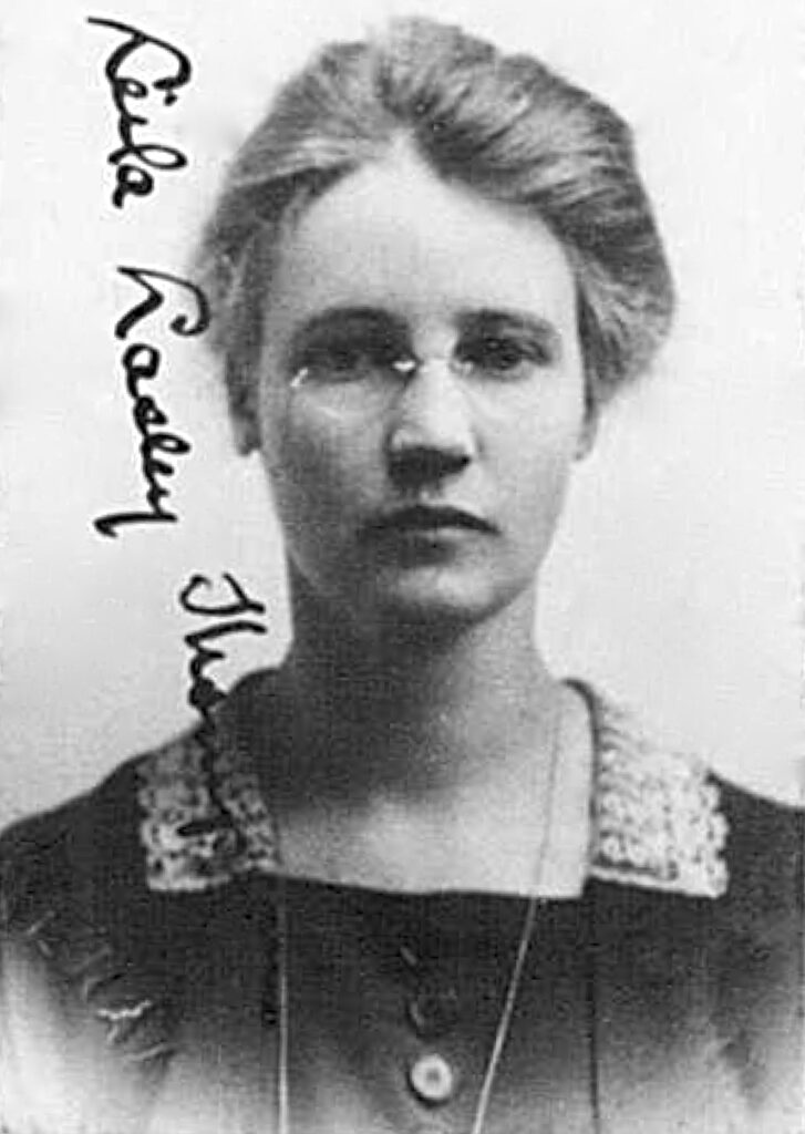 A white woman wearing glasses, with her hair pulled back.