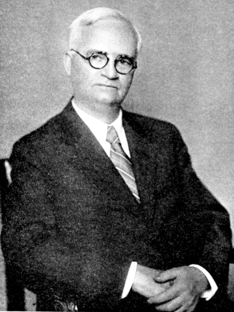 Portrait photograph of a white man in a suit and tie.