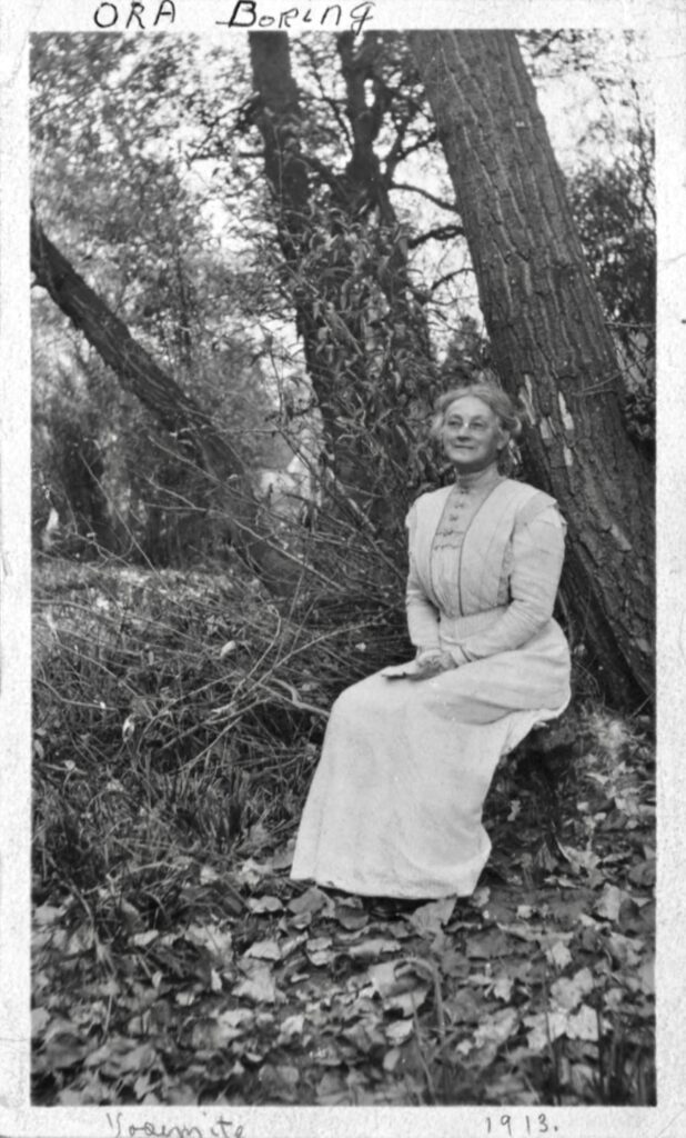Middle aged woman in early twentieth century dress sitting under a tree