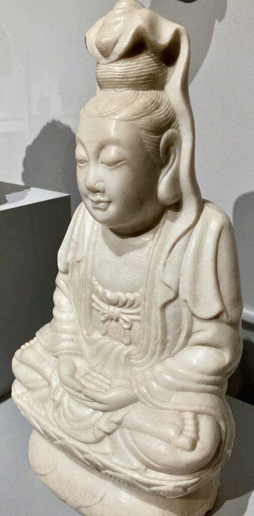 Sculpture of a female figure seated in lotus position.