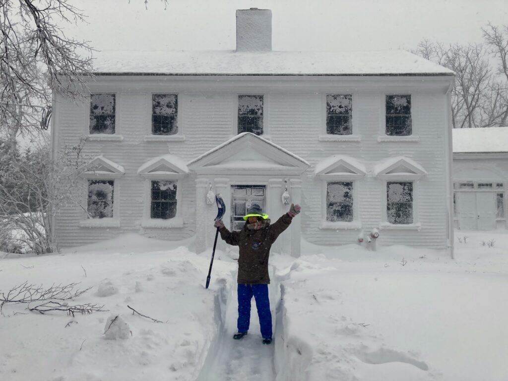 Woman standing in front of a snow-covered house.
